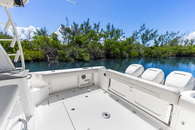 Slide: The Image of 2018 Boston Whaler 345 Conquest boat deck with outboard motors, surrounded by lush greenery. - 19