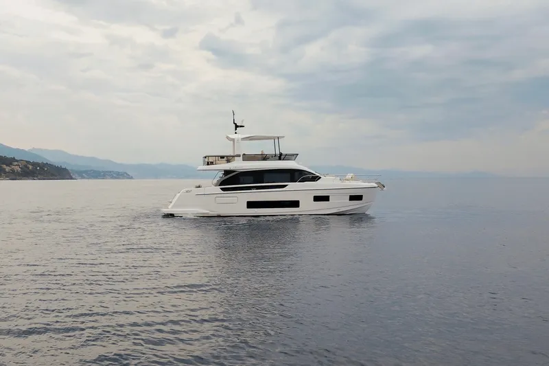 Slide: The Image of The 2027 Azimut Fly 62 cruises smoothly on calm waters under a cloudy sky. - 2