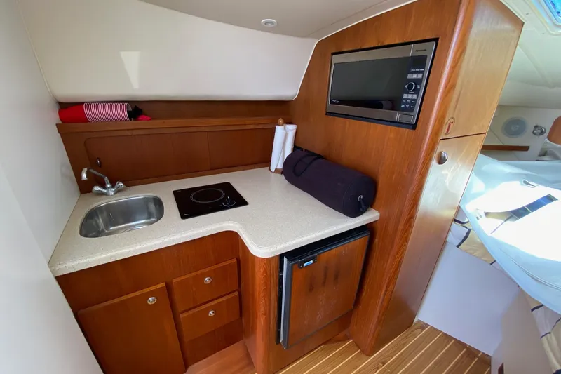 Slide: The Image of Compact galley in 2006 Tiara Yachts 2900 Open Classic, featuring sink, stove, microwave, and fridge. - 25