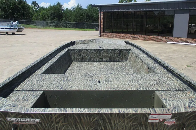 Slide: The Image of 2027 Tracker Grizzly 1754 Utility boat with camouflage design, parked outdoors. - 2
