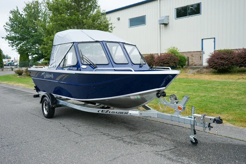 The Image of 2027 Weldcraft 180 Rebel boat on trailer, parked outdoors near industrial building. - 1