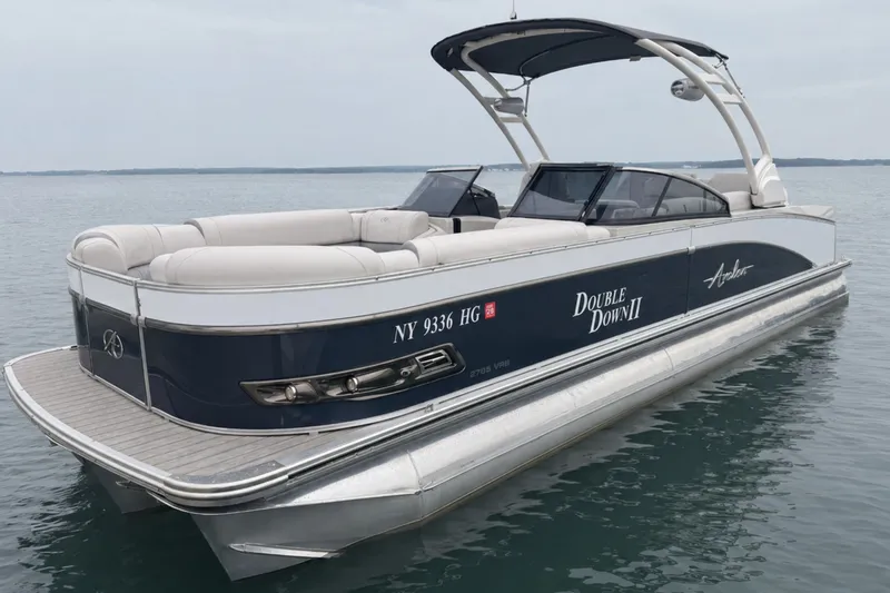 Slide: The Image of 2022 Avalon Catalina Platinum boat with versatile rear bench and windshield on calm water. - 2