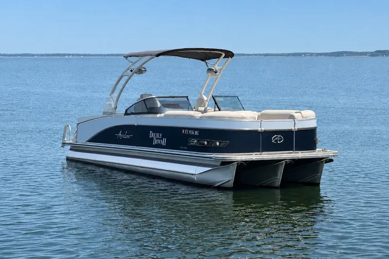 The Image of 2022 Avalon Catalina Platinum boat on calm water, featuring versatile rear bench and windshield. - 0