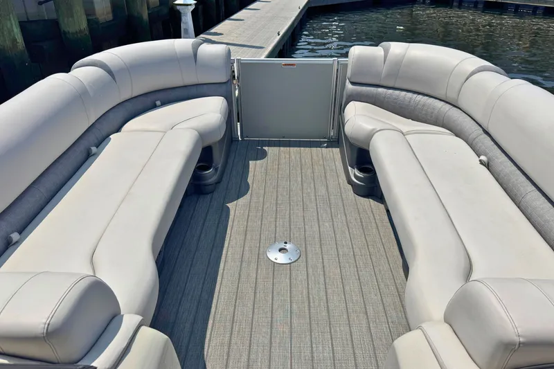 Slide: The Image of 2022 Avalon Catalina Platinum boat interior with plush seating and rear bench, docked by water. - 18
