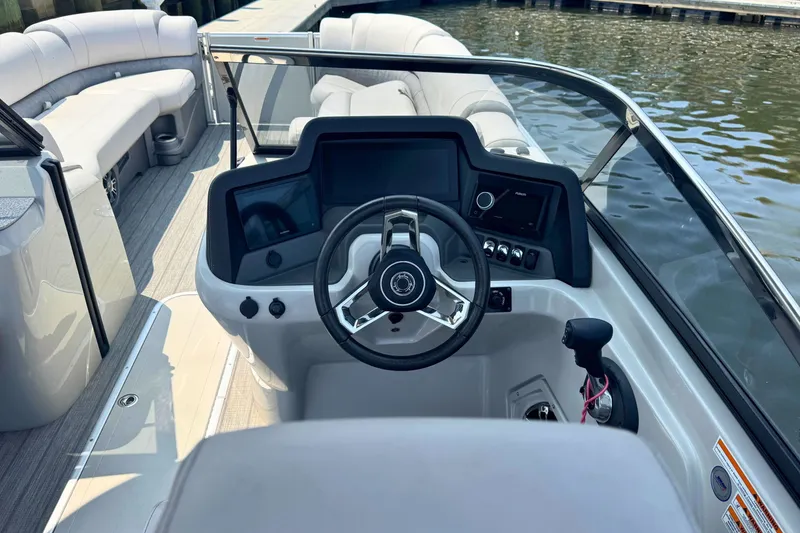 Slide: The Image of 2022 Avalon Catalina Platinum boat dashboard with steering wheel and controls, docked by water. - 16