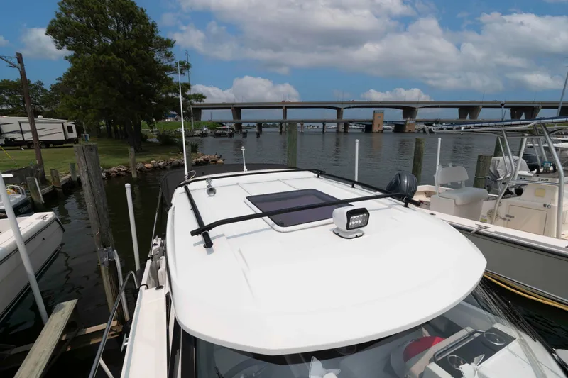 Slide: The Image of 2024 Jeanneau NC 795 Series 2 boat docked near a scenic bridge and trees. - 8