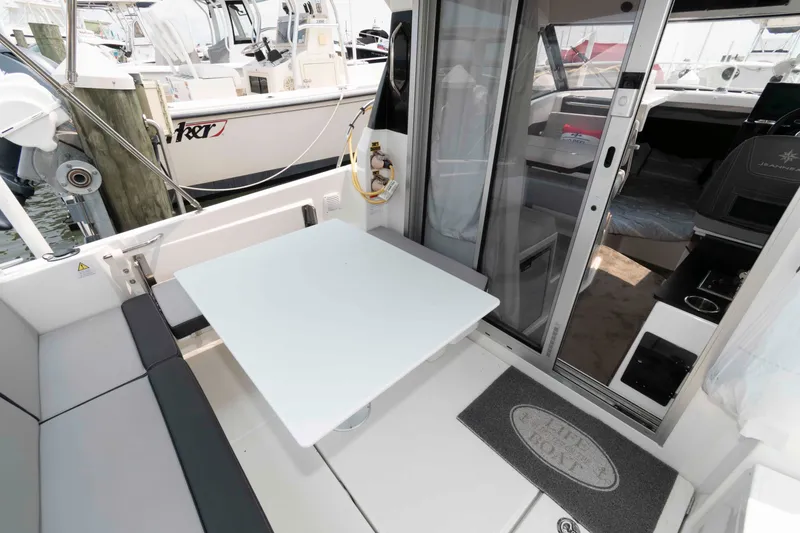 Slide: The Image of 2024 Jeanneau NC 795 Series 2 boat interior with seating and table, docked at marina. - 2