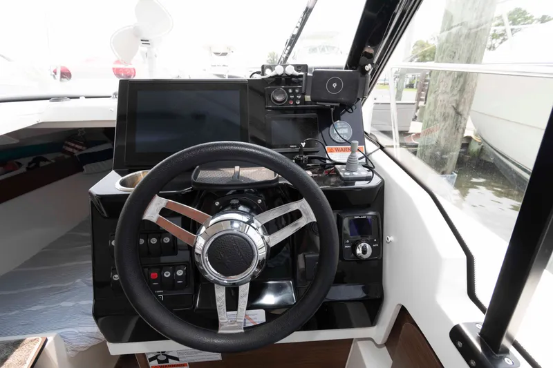 Slide: The Image of 2024 Jeanneau NC 795 Series 2 boat cockpit with steering wheel and navigation controls. - 14