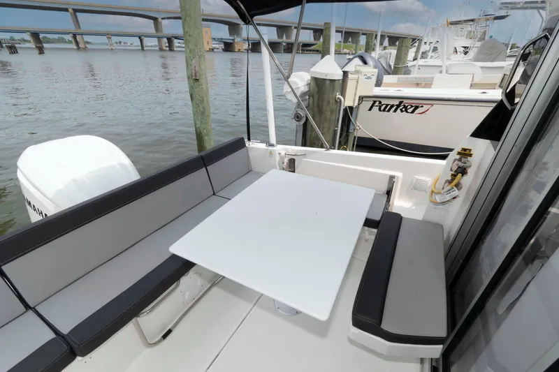 Slide: The Image of 2024 Jeanneau NC 795 Series 2 boat with outdoor seating and table, docked by a bridge. - 4