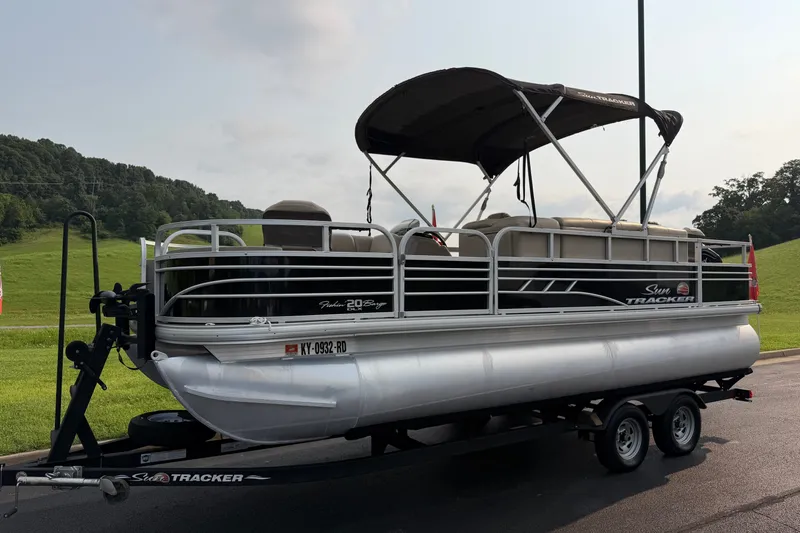 Slide: The Image of 2021 Sun Tracker Fishin' Barge 20 DLX pontoon boat on trailer, parked outdoors. - 28