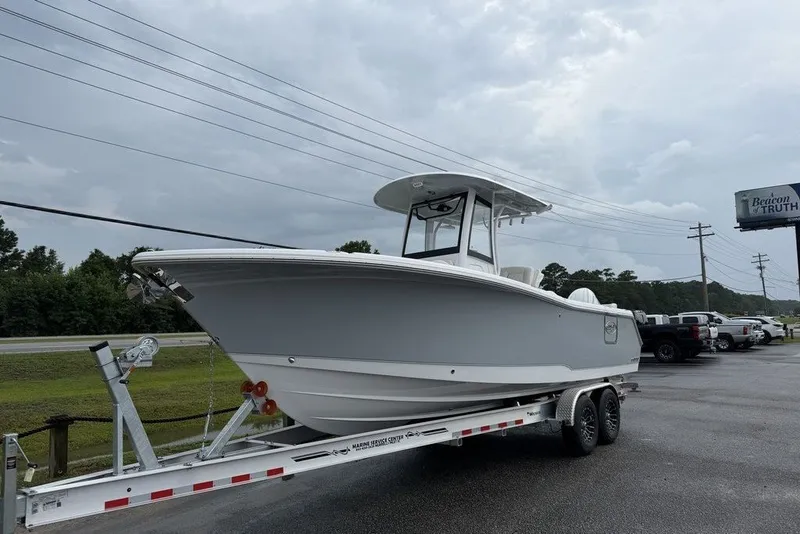 Slide: The Image of 2027 Sea Hunt Ultra 265 SE boat on trailer, parked outdoors under cloudy sky. - 2
