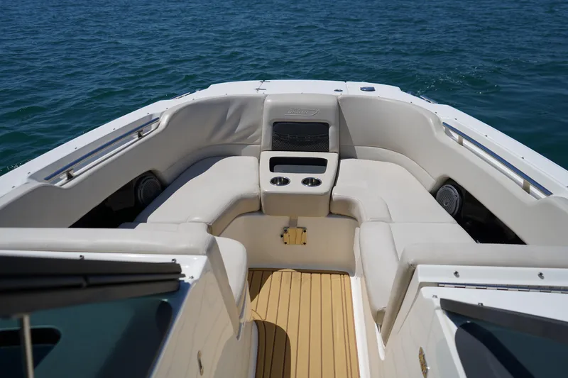 Slide: The Image of 2019 Boston Whaler 270 Vantage boat interior with cushioned seating and cup holders on open water. - 10