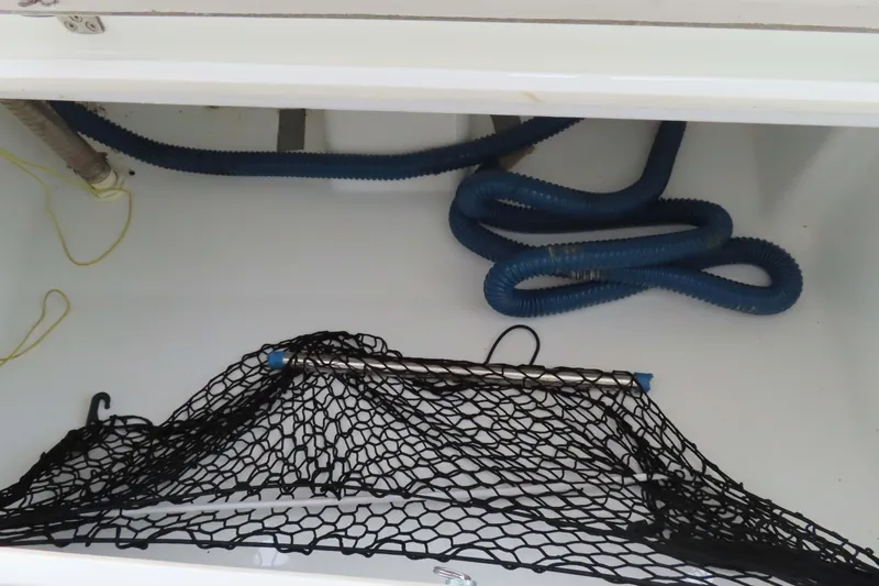Slide: The Image of Storage compartment of 2010 Fountaine Pajot Lipari 41 with blue hoses and netting. - 35