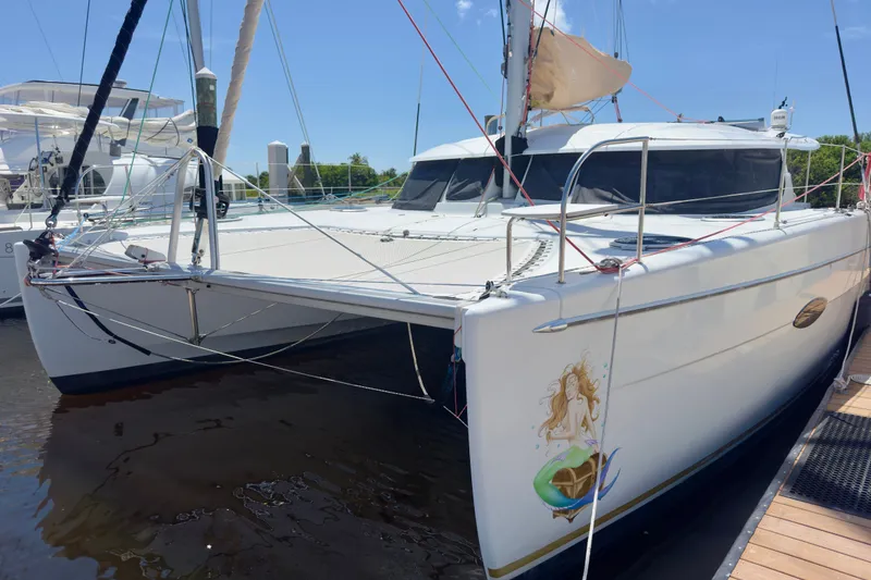 Slide: The Image of 2010 Fountaine Pajot Lipari 41 catamaran docked, featuring a mermaid design on the hull. - 2