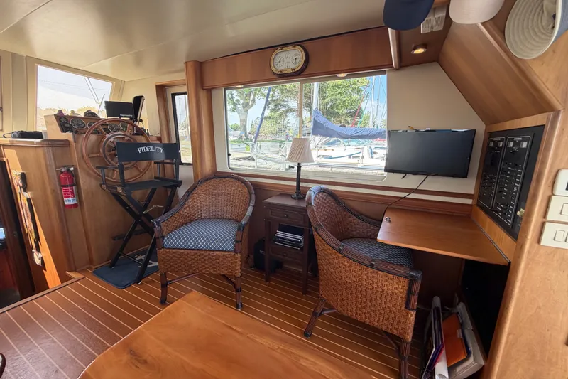 Slide: The Image of 2006 Mainship 34 Trawler interior with helm, wicker chairs, and wooden accents. - 70