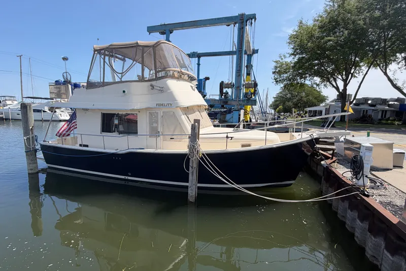 Slide: The Image of 2006 Mainship 34 Trawler docked at marina, featuring classic design and American flag. - 1