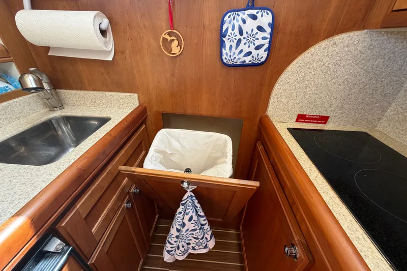 Slide: The Image of 2006 Mainship 34 Trawler kitchen with sink, stove, and pull-out trash bin. - 84