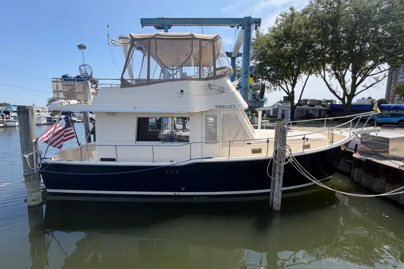 The Image of 2006 Mainship 34 Trawler docked at marina, featuring American flag and canopy. - 0