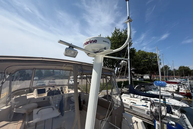 Slide: The Image of 2006 Mainship 34 Trawler at marina, featuring radar and cockpit view under clear sky. - 44
