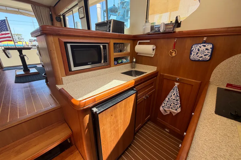 Slide: The Image of 2006 Mainship 34 Trawler interior kitchen with microwave, sink, and wooden cabinetry. - 83