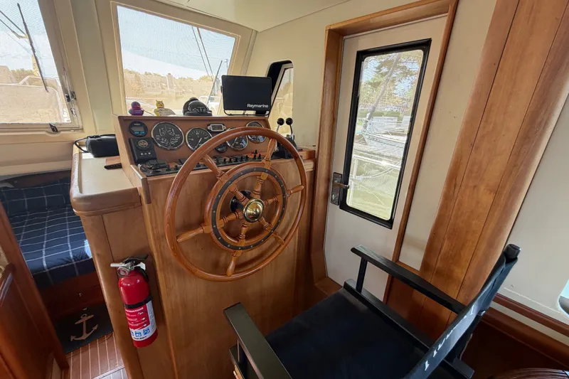 Slide: The Image of 2006 Mainship 34 Trawler helm with wooden wheel, gauges, and navigation equipment. - 75