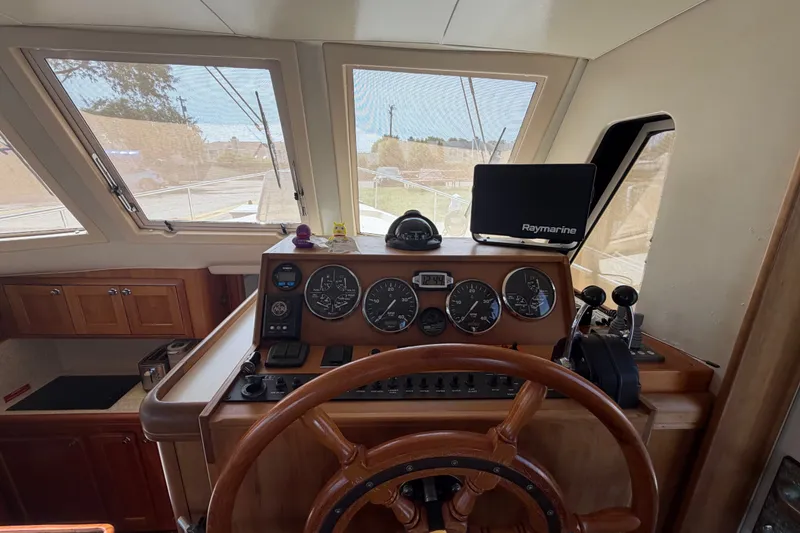 Slide: The Image of 2006 Mainship 34 Trawler helm with gauges, wooden wheel, and Raymarine navigation system. - 76