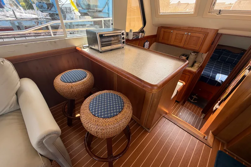 Slide: The Image of Interior of 2006 Mainship 34 Trawler with kitchenette, stools, and cozy seating area. - 68