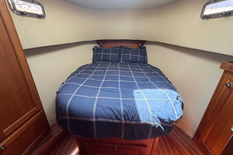 Slide: The Image of Cozy cabin bedroom in 2006 Mainship 34 Trawler with plaid bedding and wooden accents. - 86