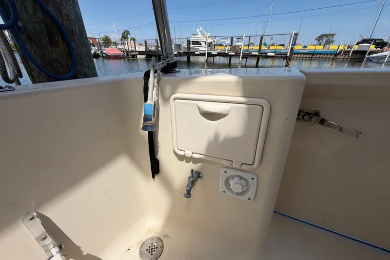 Slide: The Image of 2006 Mainship 34 Trawler deck with storage compartment and water faucet, docked at marina. - 14