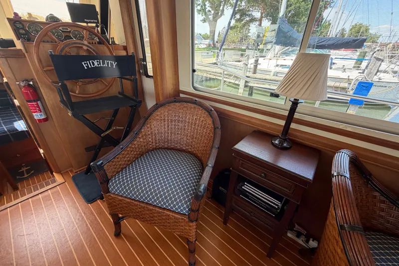 Slide: The Image of Interior of 2006 Mainship 34 Trawler with wicker chair, lamp, and marina view. - 73