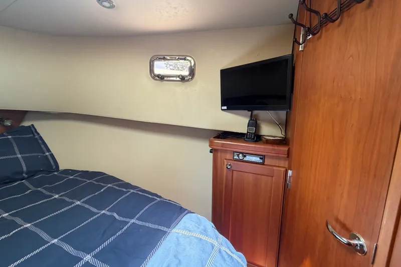 Slide: The Image of Cozy cabin interior of 2006 Mainship 34 Trawler with bed, TV, and wooden cabinetry. - 88