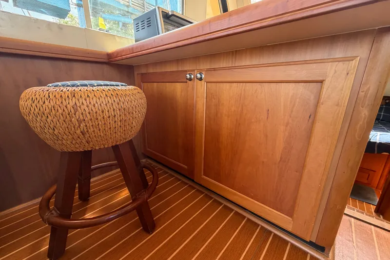 Slide: The Image of Interior of 2006 Mainship 34 Trawler with wooden cabinetry and woven stool. - 69