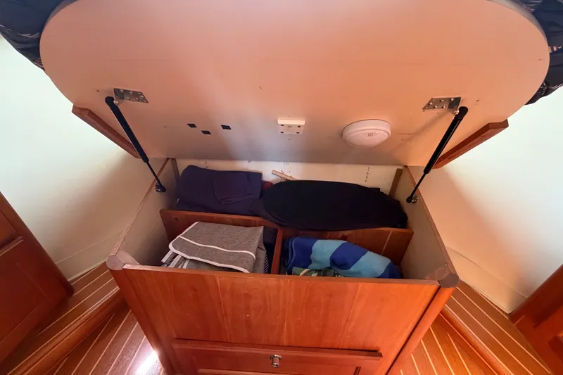 Slide: The Image of Under-bed storage in 2006 Mainship 34 Trawler, featuring organized compartments and wooden flooring. - 87