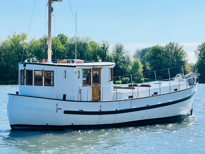 Slide: The Image of 1955 Colin Archer 42 boat on a calm river with lush green trees in the background. - 4