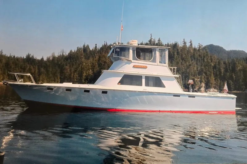Slide: The Image of 1984 Raymond Hunt Sport Fisher yacht on calm water, surrounded by forested landscape. - 39