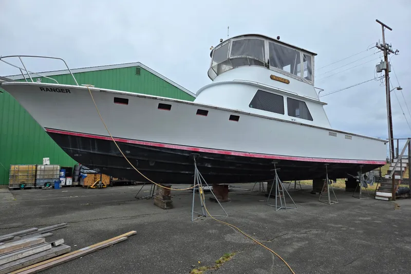Slide: The Image of 1984 Raymond Hunt Sport Fisher boat on stands, named "Ranger," in a shipyard setting. - 1