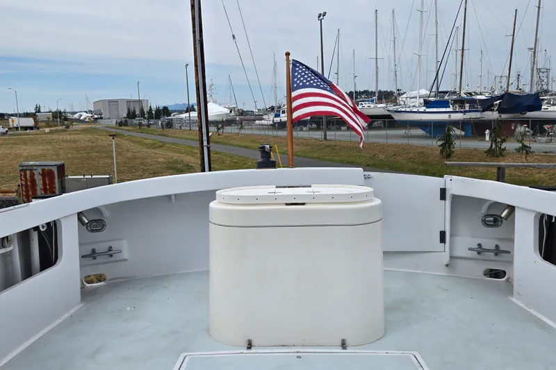 Slide: The Image of 1984 Raymond Hunt Sport Fisher boat with American flag, docked near marina with sailboats. - 20