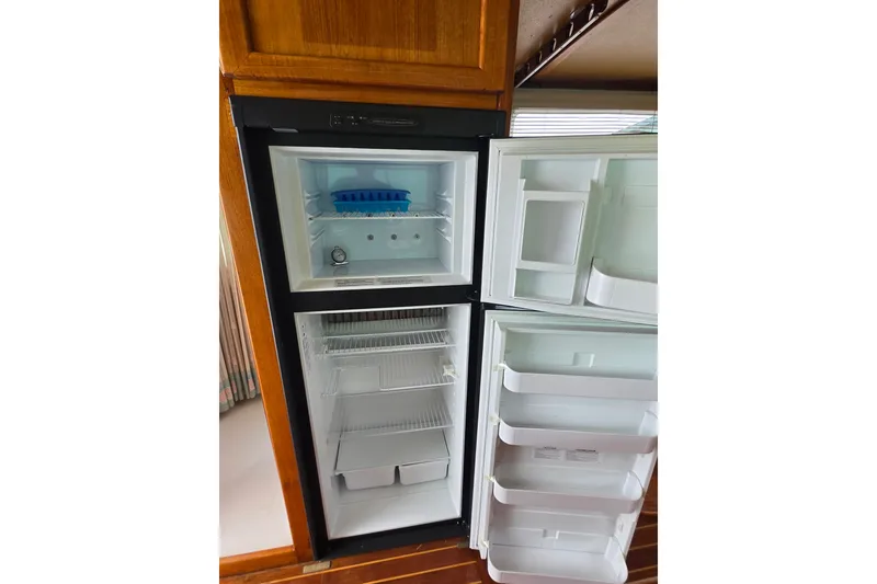 Slide: The Image of Open refrigerator on 1984 Raymond Hunt Sport Fisher boat, showcasing freezer and fridge compartments. - 26