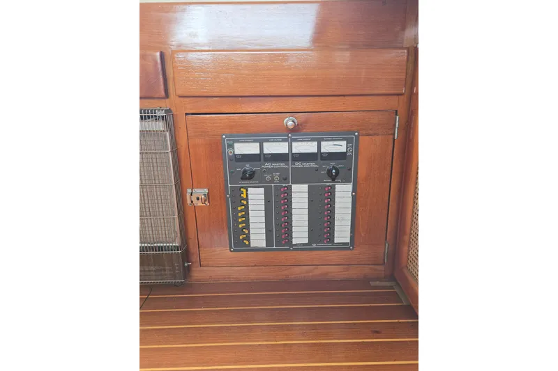Slide: The Image of Electrical panel on 1984 Raymond Hunt Sport Fisher boat, featuring wooden cabinetry and control switches. - 9