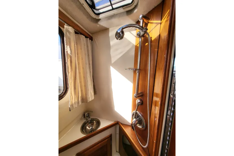 Slide: The Image of 1984 Raymond Hunt Sport Fisher bathroom with shower, sink, and window curtain. - 17