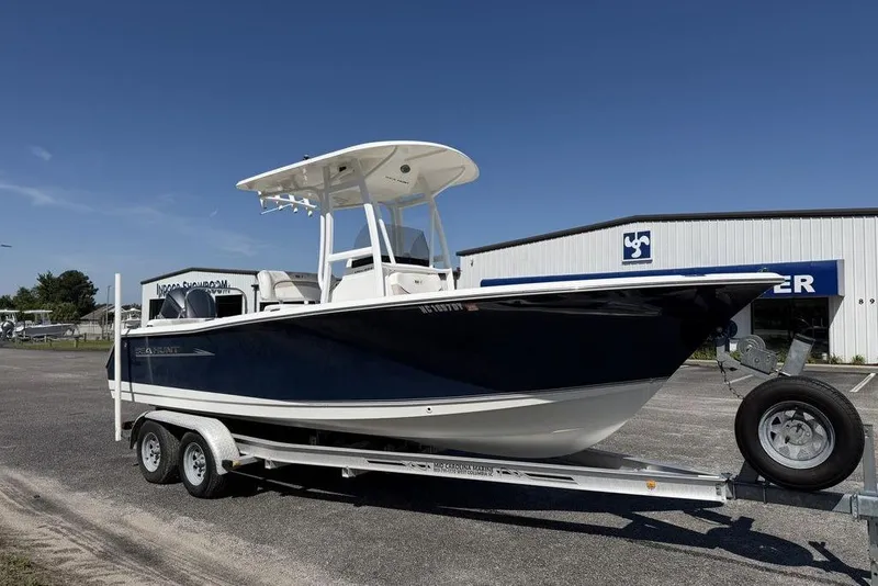 Slide: The Image of 2013 Sea Hunt Ultra 234 boat on trailer, parked outside a showroom under clear blue sky. - 6