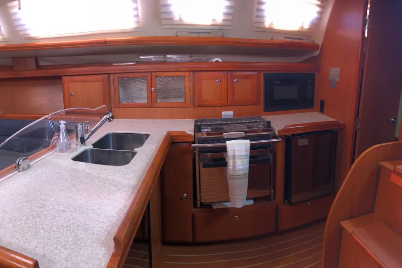Slide: The Image of 2008 Hunter 38 yacht interior kitchen with sink, stove, and wooden cabinetry. - 7