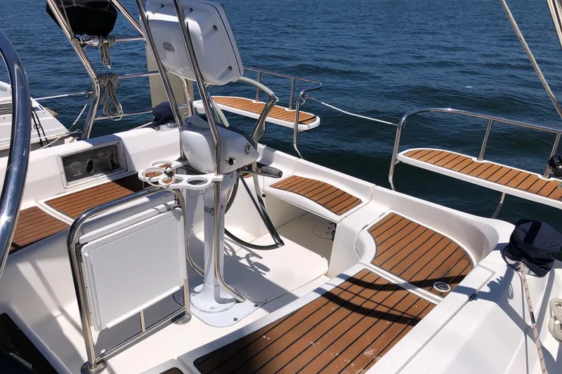 Slide: The Image of 2008 Hunter 38 sailboat cockpit with teak seating and steering wheel, overlooking the ocean. - 24