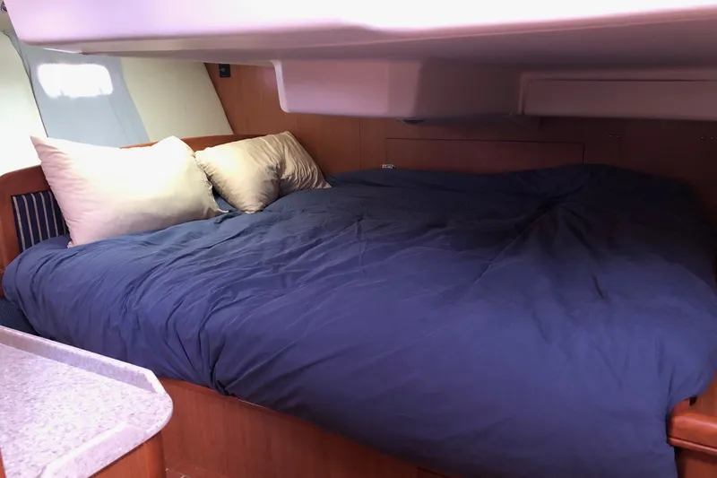 Slide: The Image of Cozy cabin bed in a 2008 Hunter 38 sailboat, featuring blue bedding and pillows. - 11