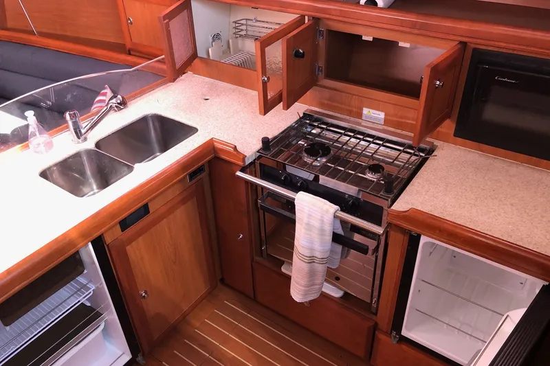 Slide: The Image of 2008 Hunter 38 yacht kitchen with dual sinks, stove, and wooden cabinetry. - 8