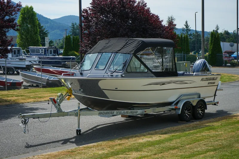 Slide: The Image of 2026 Alumaweld Intruder Outboard 22 boat on trailer, parked outdoors with scenic background. - 17