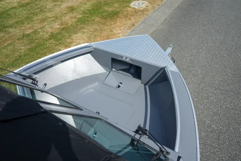 Slide: The Image of 2026 Alumaweld Intruder Outboard 22 boat bow with diamond plate deck, parked on pavement. - 16