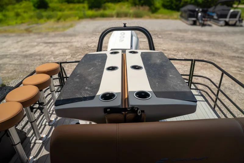 Slide: The Image of The image shows the deck of a Starcraft RX 25 DL BAR boat with bar stools and a table. - 14