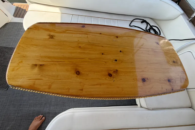 Slide: The Image of A glossy wooden table on a boat with white upholstery and gray carpeting. - 23
