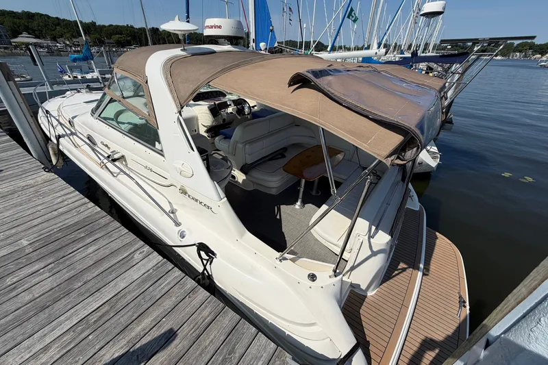 Slide: The Image of 1996 Sea Ray Sundancer 330 docked, featuring a beige canopy and spacious seating area. - 5